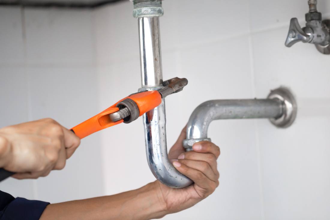 Artisan plombier réparant une canalisation